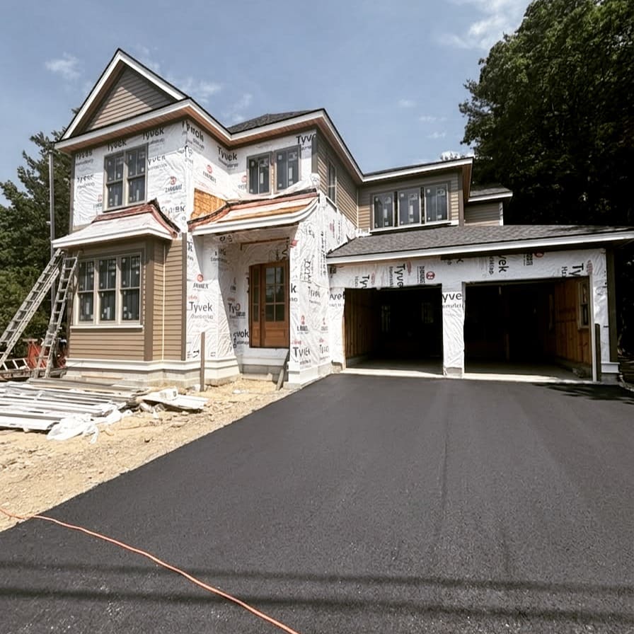 New-construction home nearing completion with a freshly paved driveway