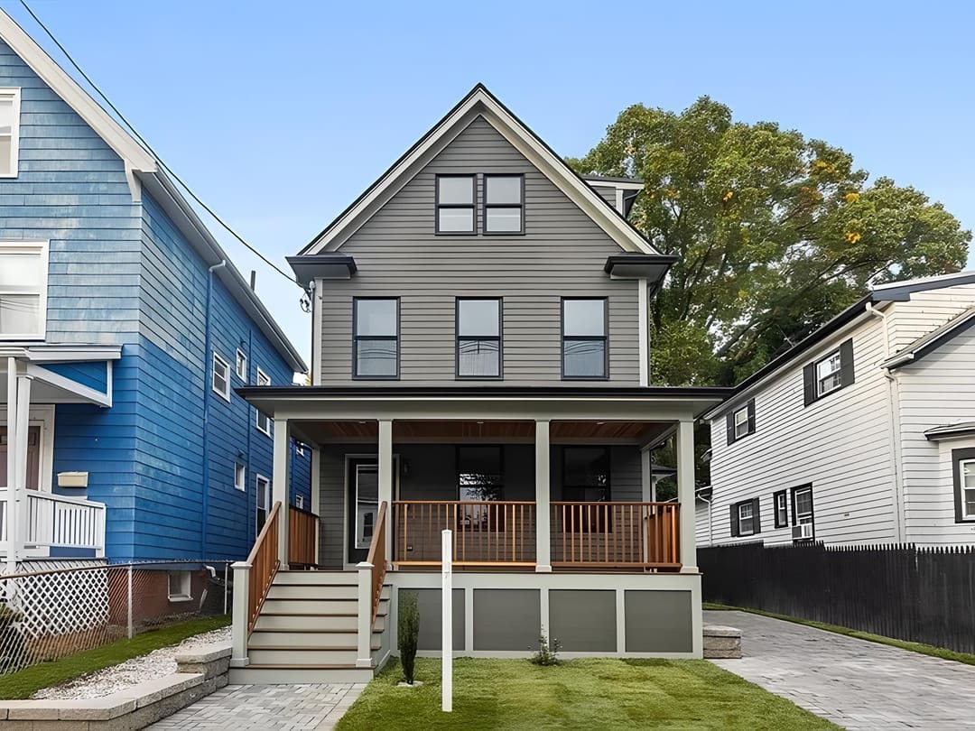 Completed grey-clapboard home with a covered porch in Somerville, Massachusetts